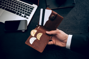 mão segurando carteira com bitcoins e cartão de crédito